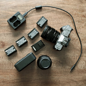 Camera with batteries and charger on a wooden surface